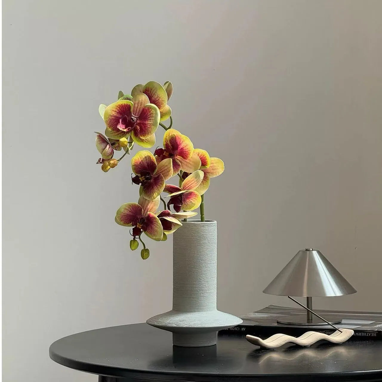 手彫りの花瓶に入ったカラフルなバタフライオーキッド – 花瓶の中の人工的なフラワーアレンジメント