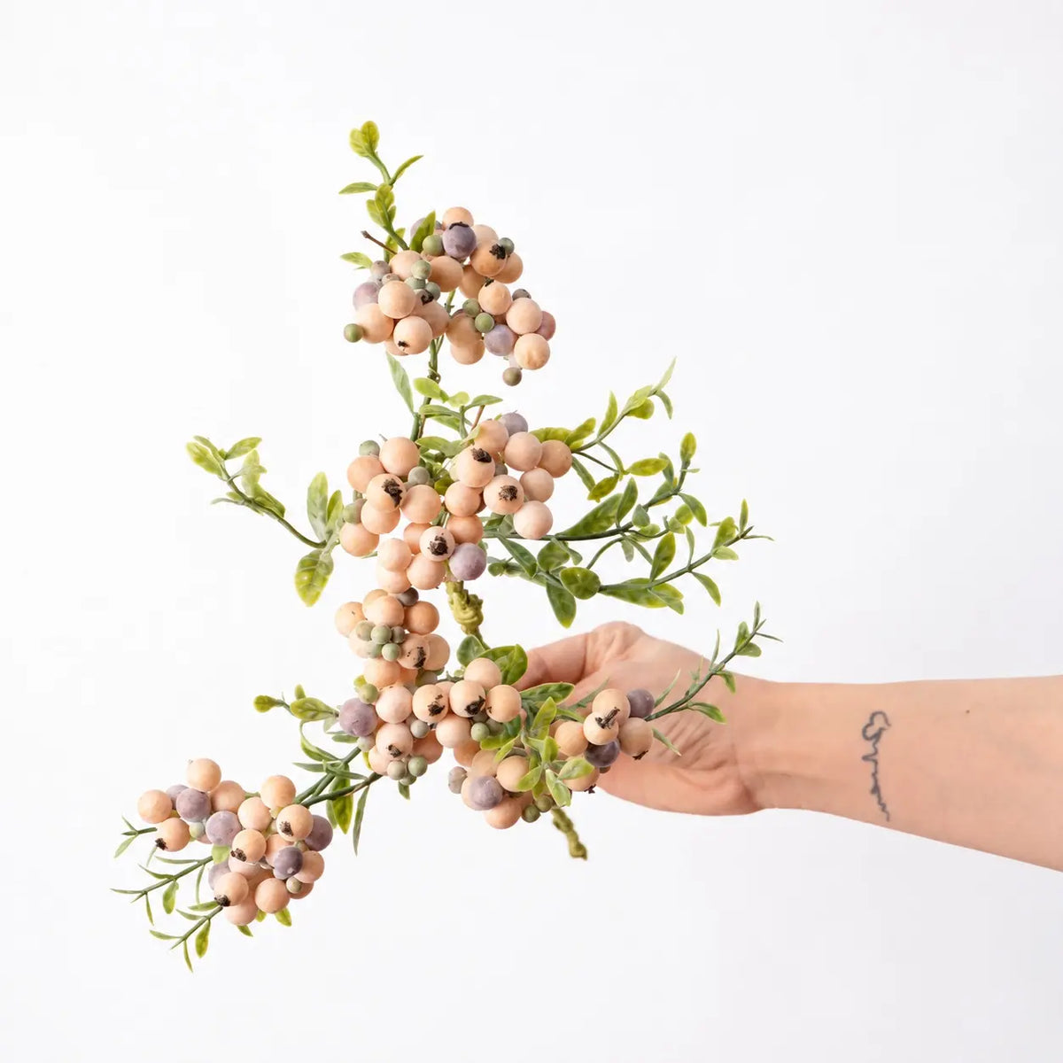 Hand-held detail of 38 cm artificial berry spray in apricot