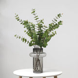Artificial eucalyptus green foliage in glass vase