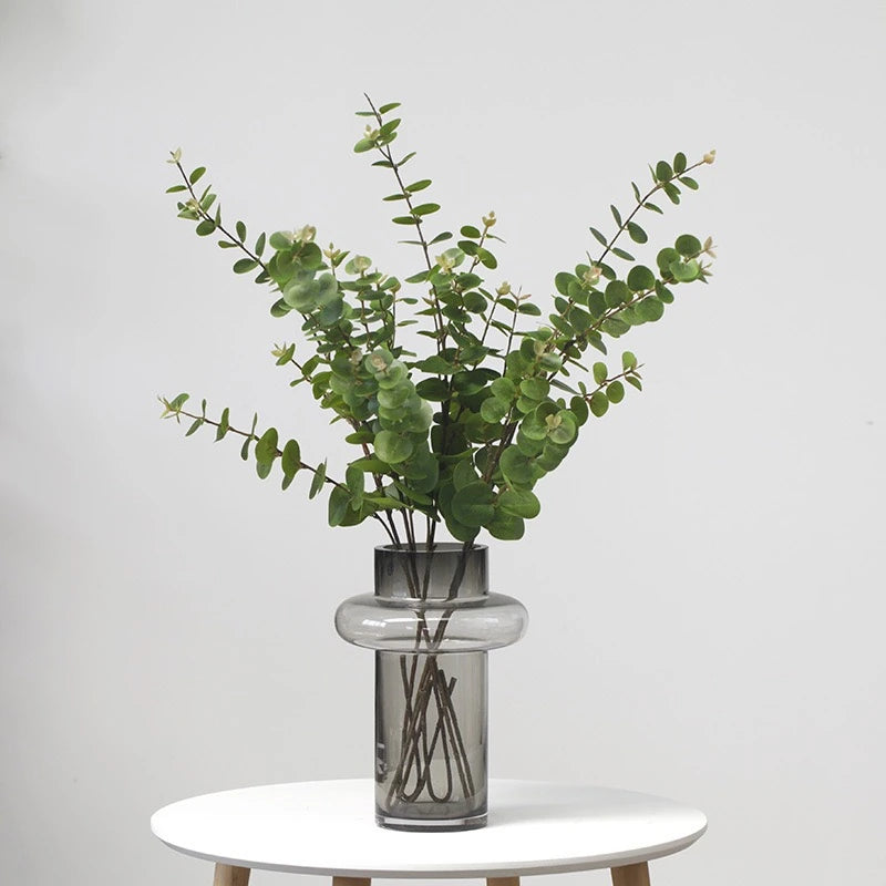 Artificial eucalyptus green foliage in glass vase