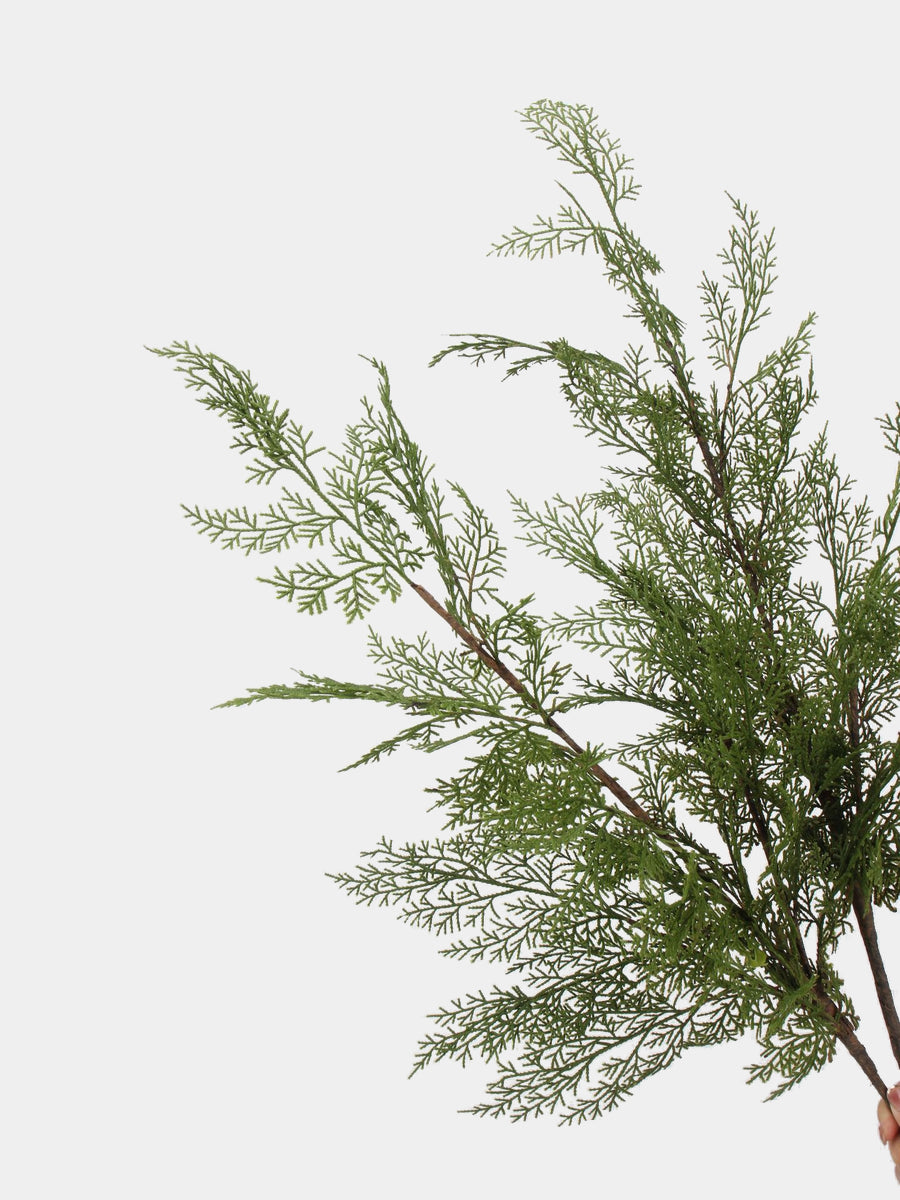 Close-up of finely divided green foliage and textured brown stems on an artificial pine branch