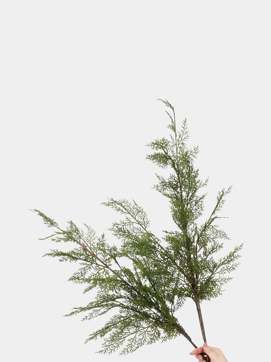 Hand-held artificial fine-leaf pine branches showing their airy green sprays and branching shape