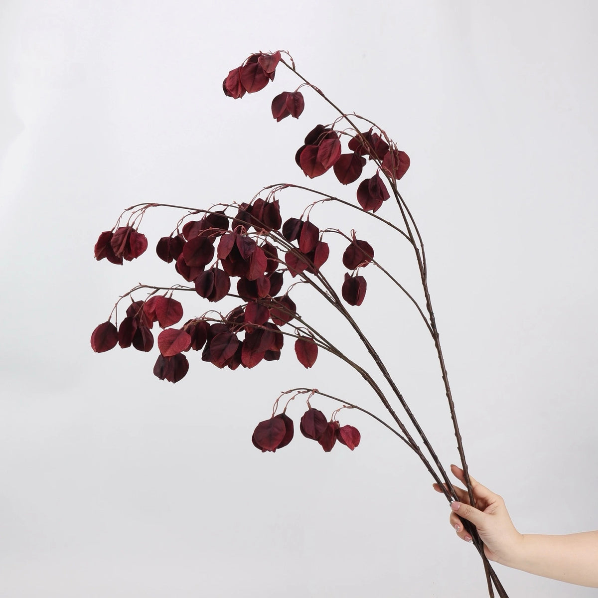 Burgundy faux lantern pod branches shown by hand