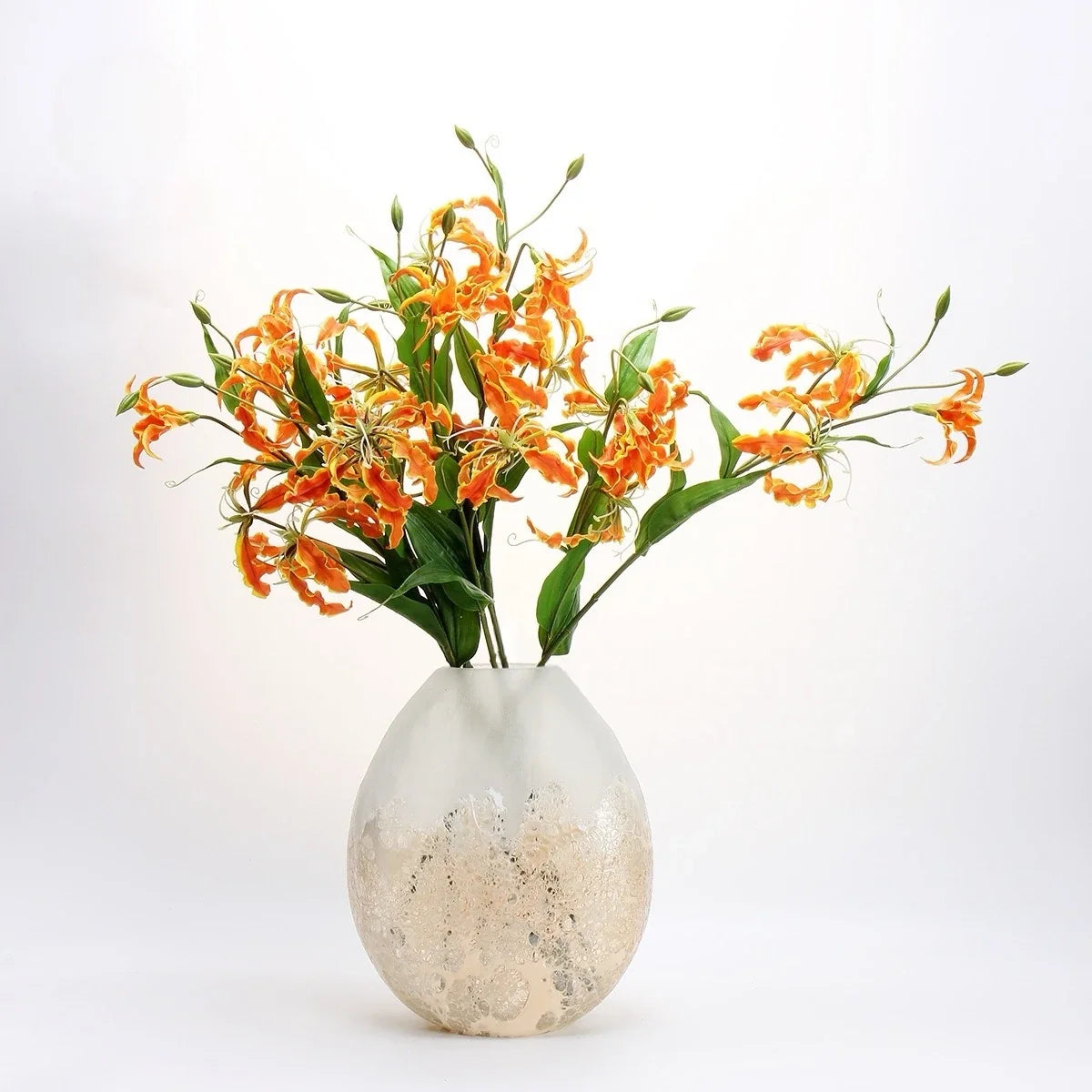 Orange artificial gloriosa lily stems arranged in a vase