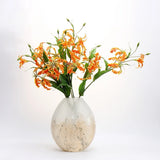 Orange artificial gloriosa lily stems arranged in a vase