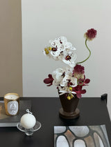 Artificial orchid arrangement styled on a dark console