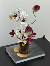 Close-up of burgundy and white faux orchid arrangement