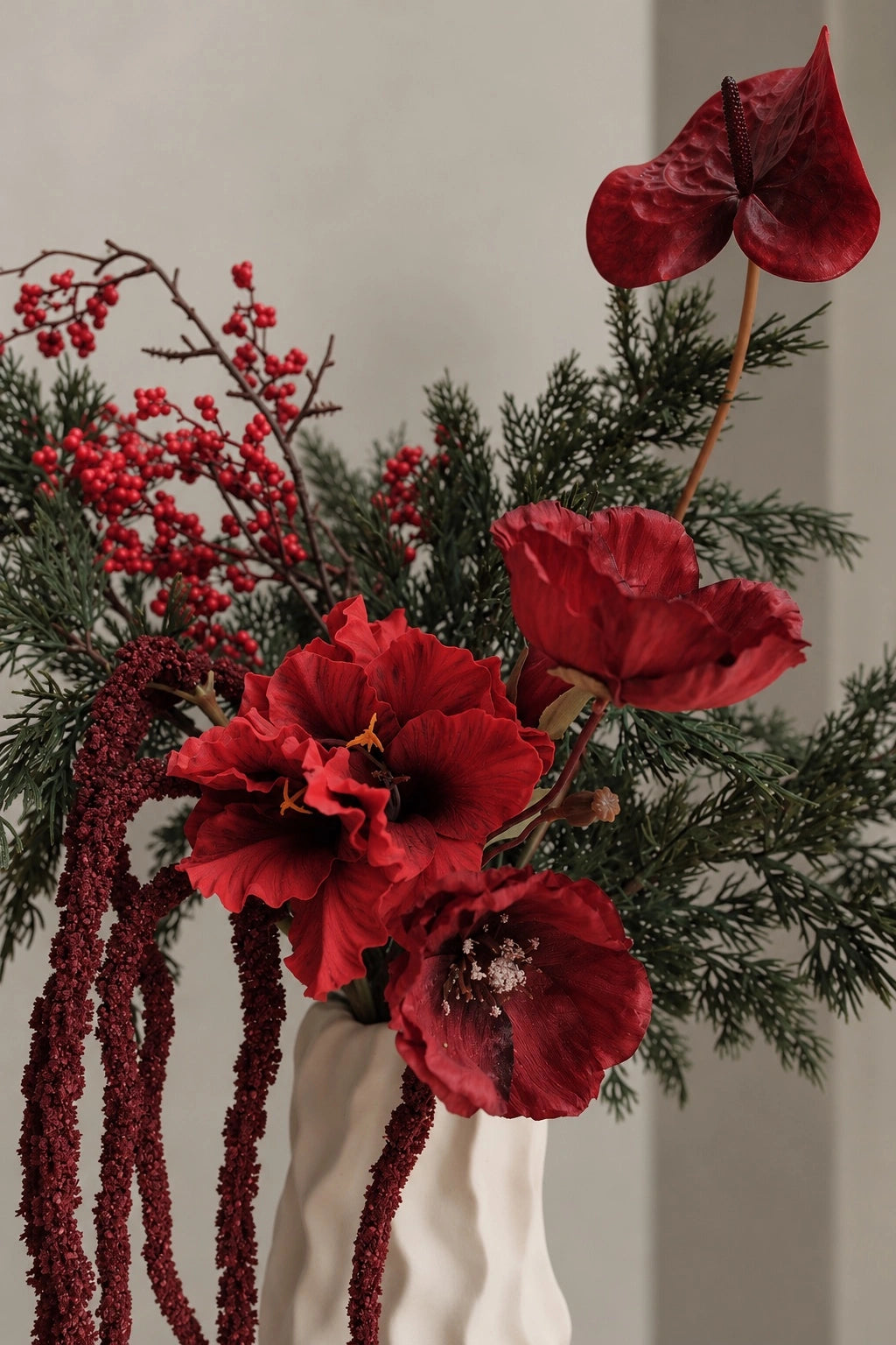 Close-up of the red blooms and trailing burgundy foliage in the Noël bouquet
