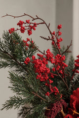Red berry clusters and evergreen foliage in the Noël Christmas bouquet
