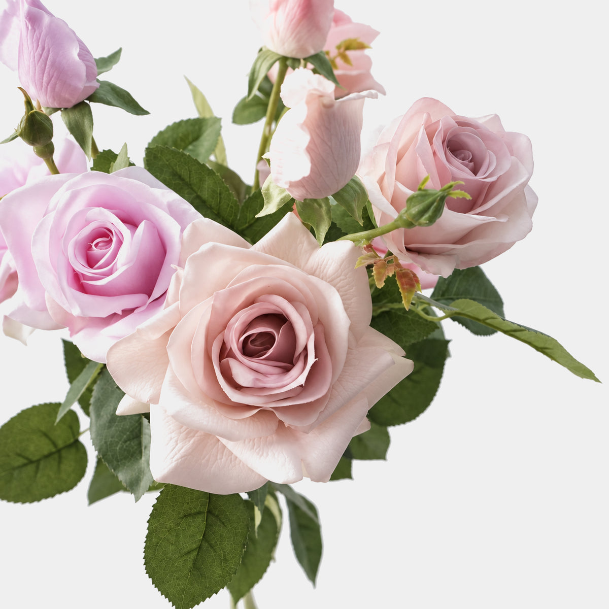 Mixed pink and lilac Real Touch artificial rose stems showing petal texture and green leaves